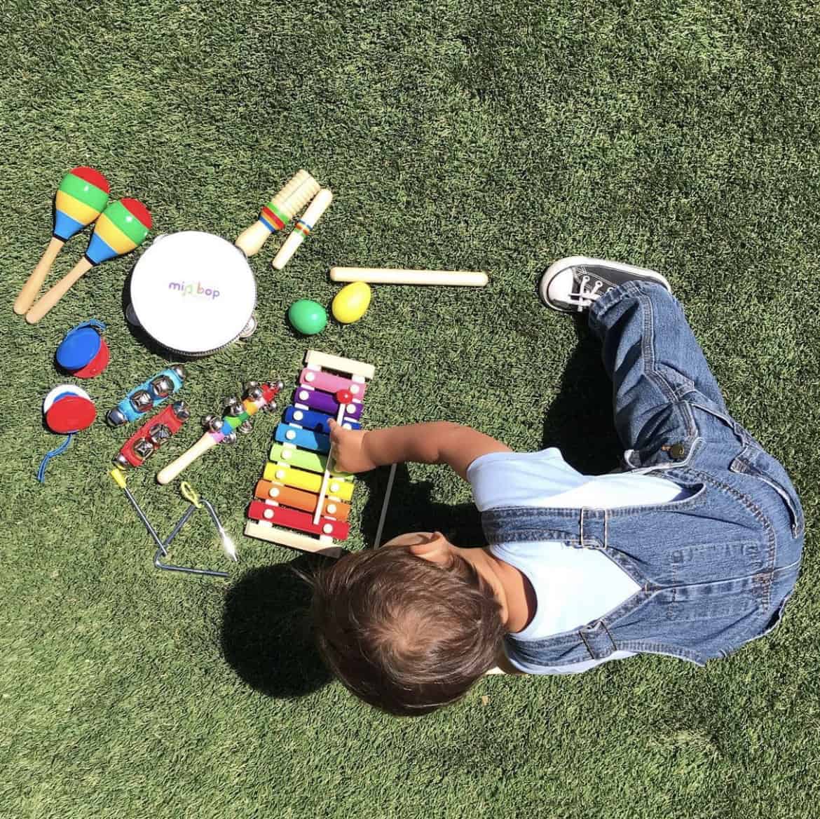 Child sitting on grass playing with instruments