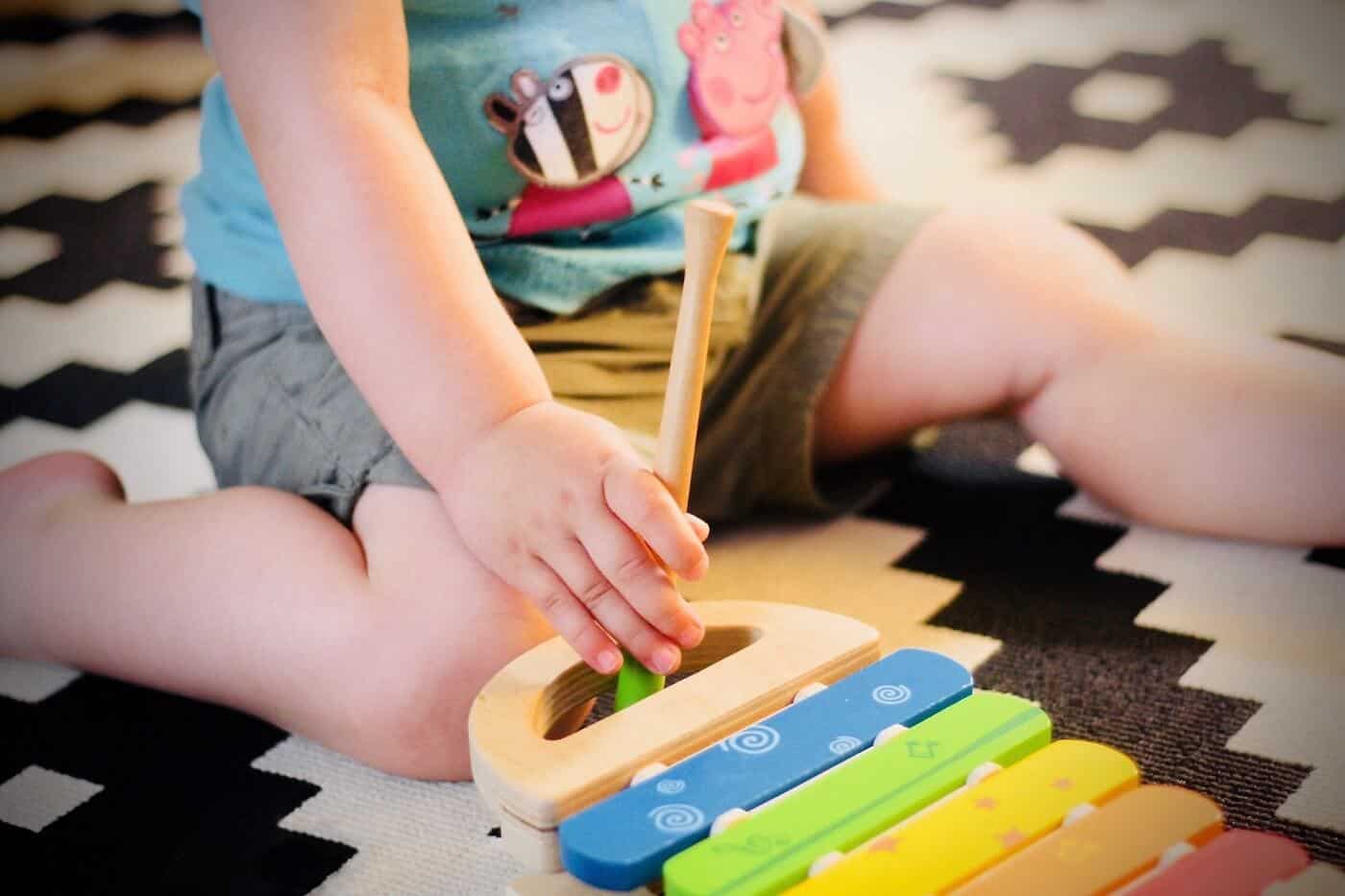 Baby playing xylophone on rug