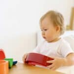 Toddler playing with puzzle toys using motor skills