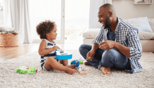 Dad teaching his toddler son how to play guitar