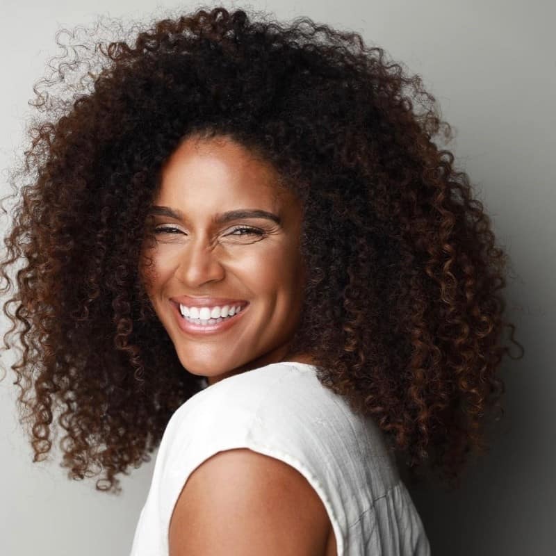 A woman with curly hair smiling at the camera.