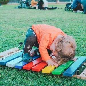 A toddler playing with a colorful xylophone in a park, creating a Boo Bop melody.