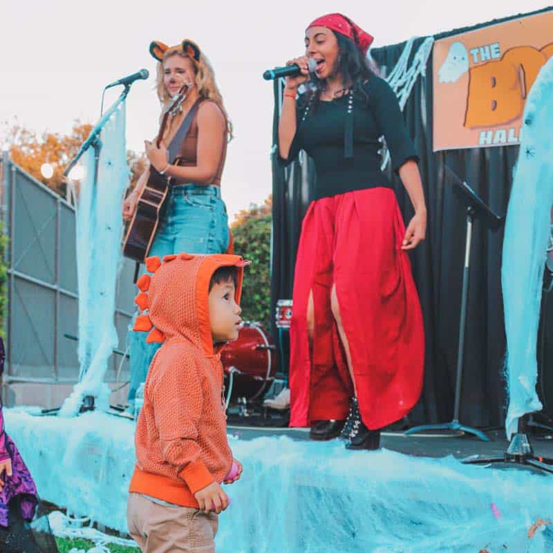 A group of children singing and doing the Boo Bop on stage at an outdoor event.