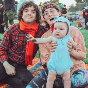 A family with a baby sitting on a blanket, enjoying a boo bop playtime.