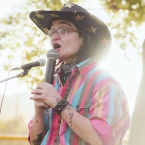 A woman in a cowboy hat is speaking into a microphone, delivering her passionate speech.