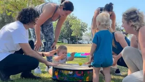 A group of people playing with a drum in a park.