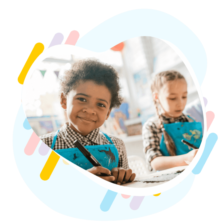 Two children sitting at a table in a classroom, engaged in a lesson.