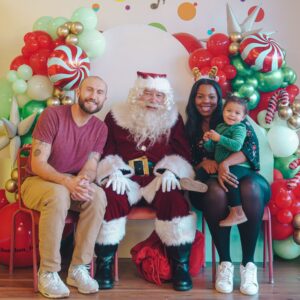 A family poses for a photo in front of a santa claus backdrop