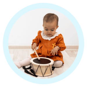 baby playing with drumset in light blue circular border