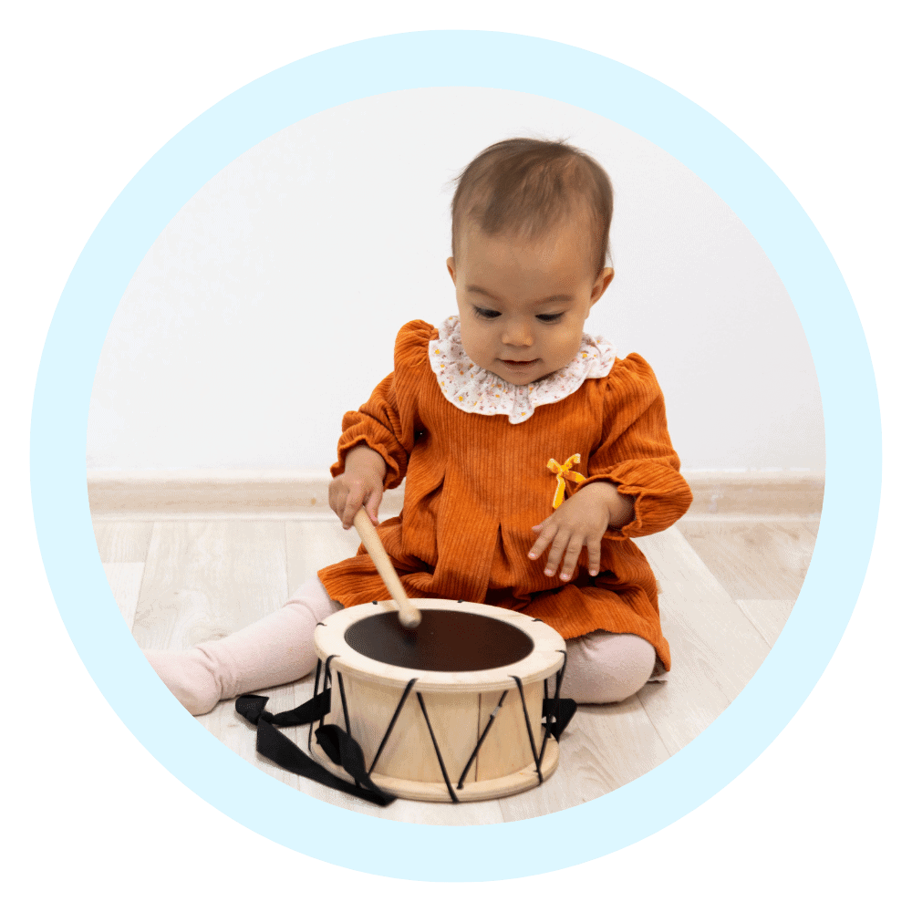 baby playing with drumset in light blue circular border